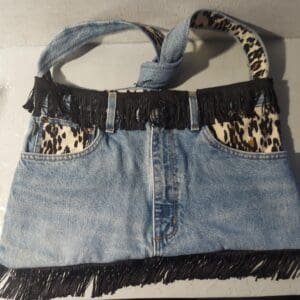 Denim handbag with leopard print and fringe details.