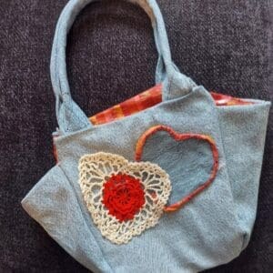 Handcrafted denim bag decorated with crochet hearts.
