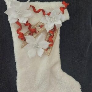 White Christmas stocking with red ribbons and a white flower decoration.