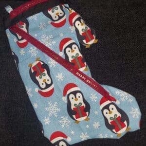 A festive stocking with penguin and snowflake patterns.