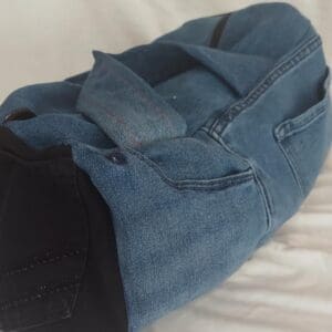 Blue denim duffel bag on bed